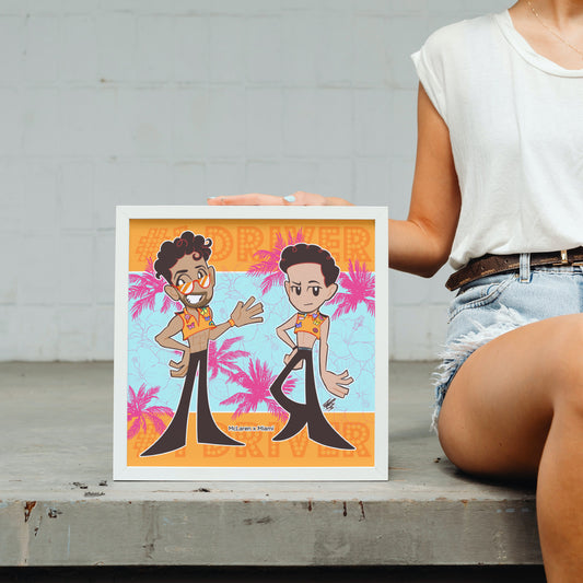 The aforementioned Miami x McLaren illustration shown in a mock-up display frame for real life reference. The frame is placed on a concrete step, where someone is holding it upright and sitting on the step next to it. Their head is out of view but you can see half of their body, wearing a white vest and light blue jeans shorts and a belt.