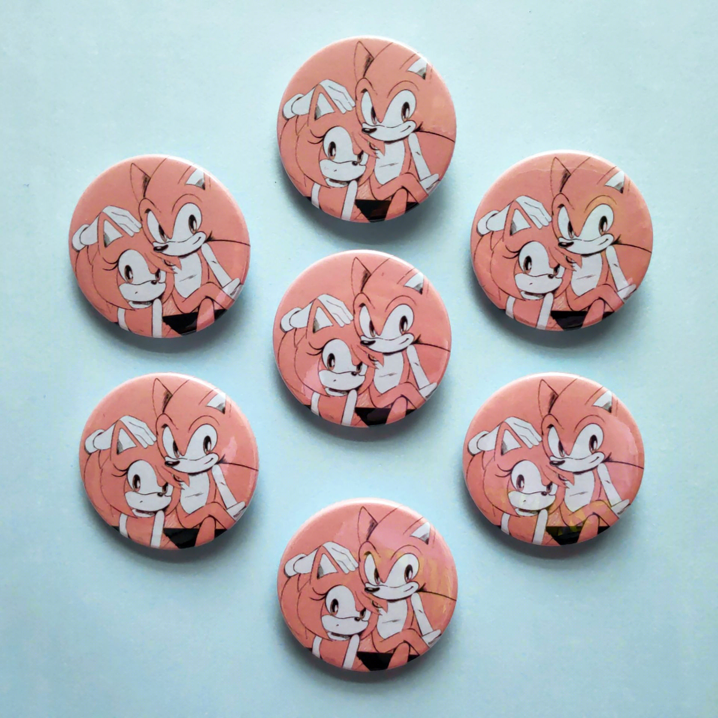 Photo of 7 pink Sonic and Amy button badges laid across a blue background.